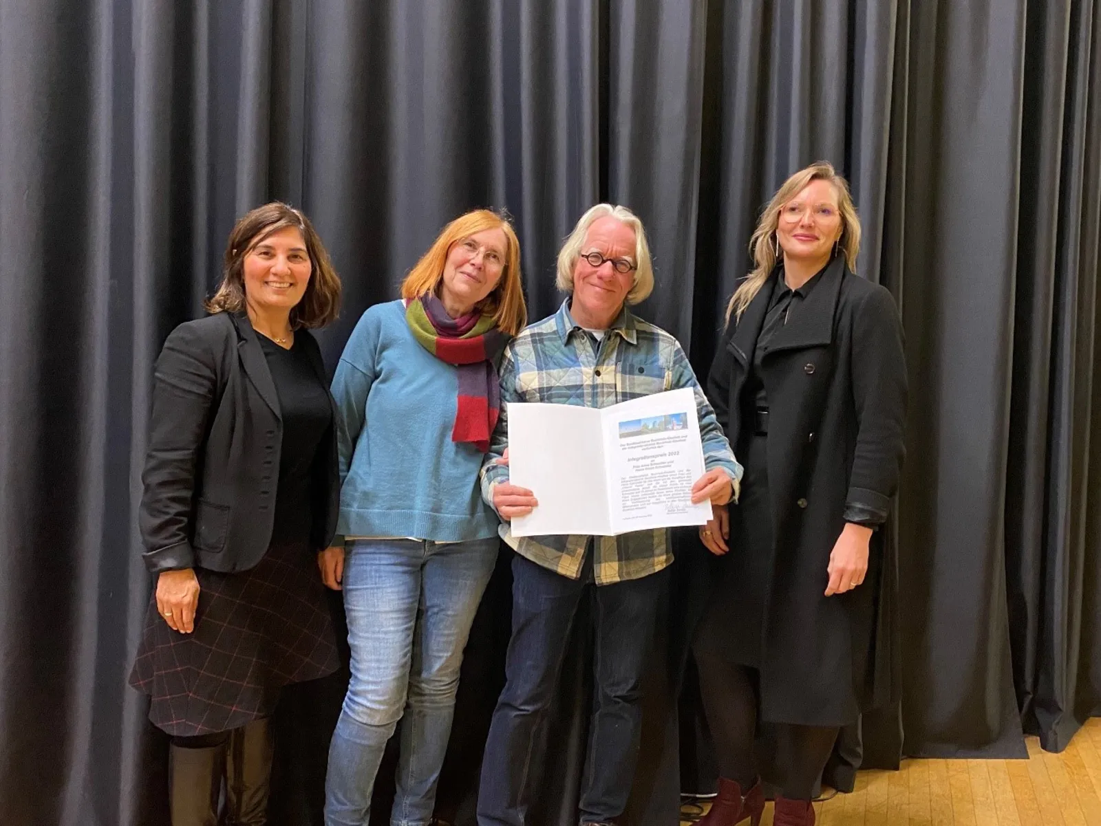 Vier Damen stehen nebeneinander für ein gemeinsaes Foto. Eine Davon hält den Integrationspreos 2022 lächeld in die Kamera.